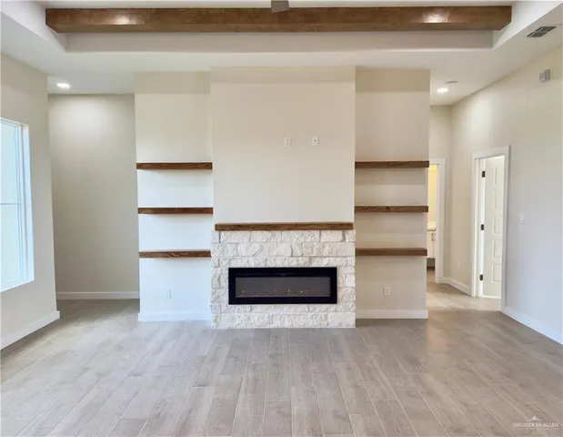 a view of kitchen and empty room with wooden floor