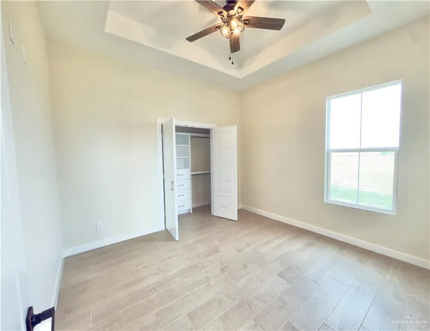 an empty room with chandelier fan and windows