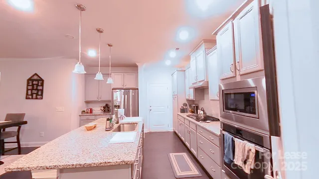 a large kitchen with kitchen island granite countertop a large counter top space a sink stainless steel appliances and cabinets