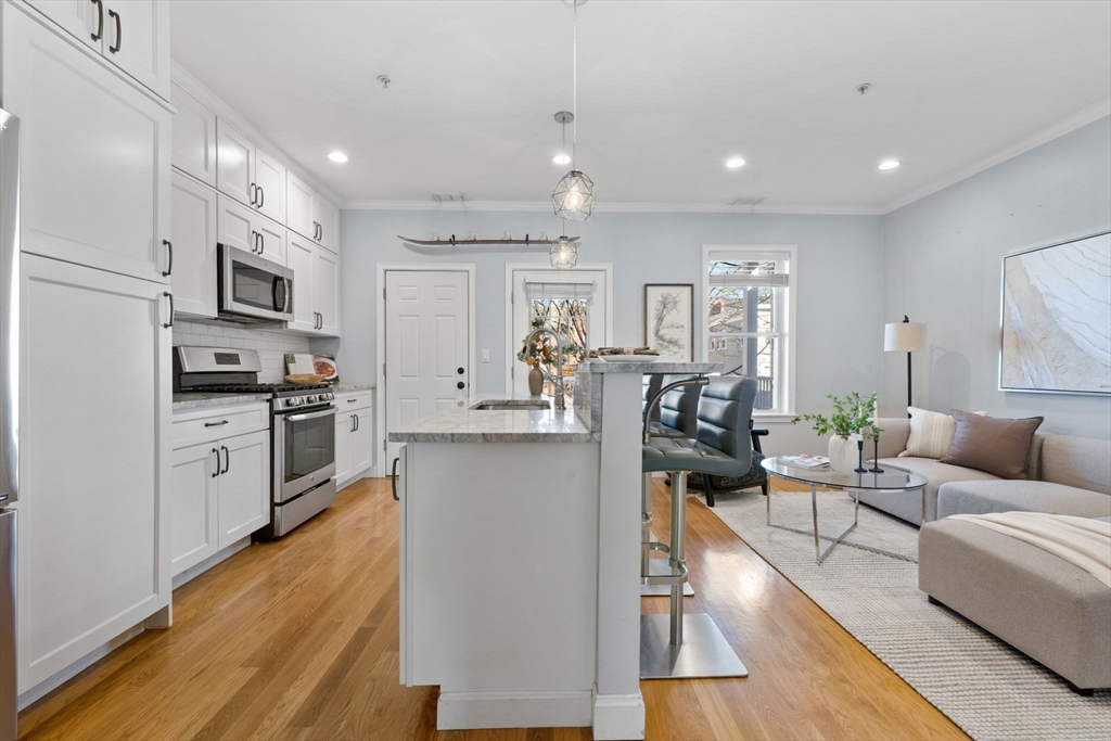 242 West Fifth Street, Unit 3 Boston, MA 02127 - Photo 7 of 37 a living room with stainless steel appliances furniture wooden floor and a kitchen view