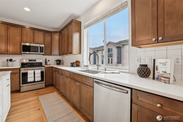 a kitchen with stainless steel appliances kitchen island granite countertop a refrigerator a sink dishwasher a stove and white cabinets with wooden floor