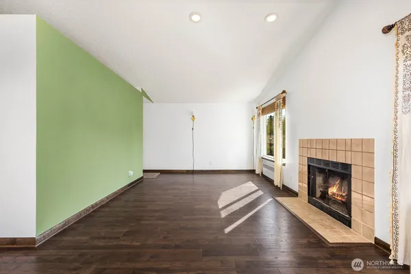 an empty room with wooden floor fireplace and windows