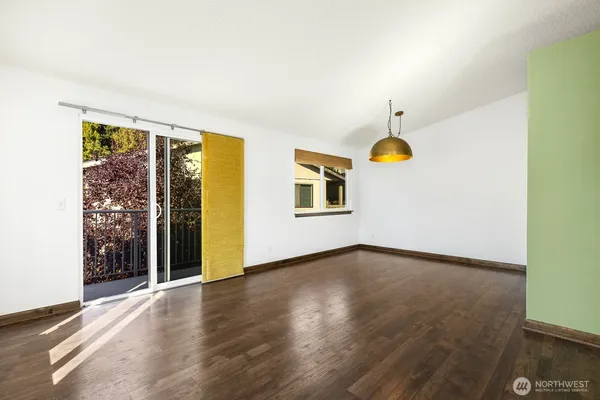 a view of an empty room with window and wooden floor