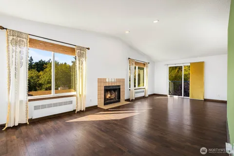 a view of a livingroom with wooden floor a fireplace and window
