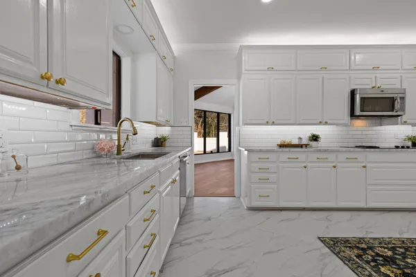 a kitchen with granite countertop white cabinets and stainless steel appliances
