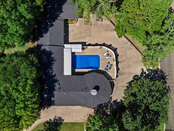 an aerial view of a house with outdoor space and trees all around
