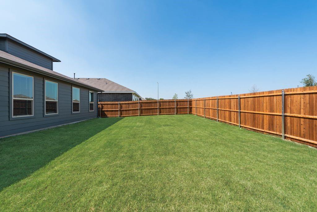 15944 Stableford Road Justin, TX 76247 - Photo 22 of 22 Expansive backyard featuring a professionally installed wood privacy fence and lush, manicured lawn