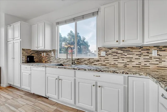 a kitchen with granite countertop white cabinets and sink