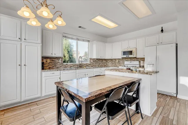 a kitchen with a table chairs microwave and cabinets