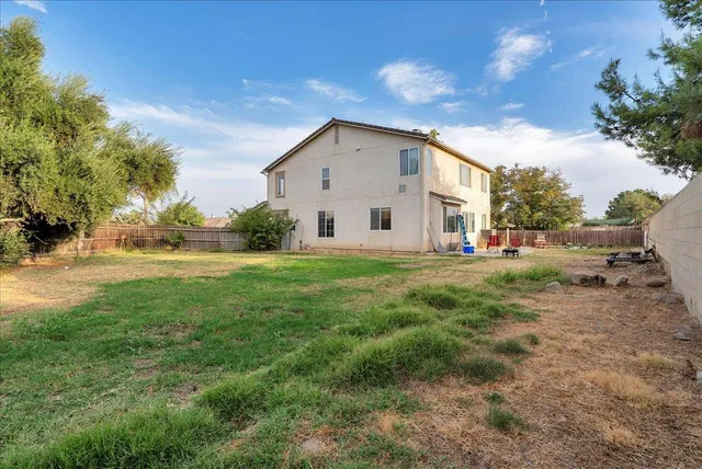 a view of a house with backyard and trees