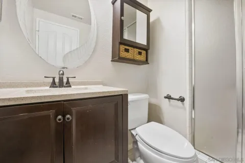 a bathroom with a granite countertop toilet sink and mirror