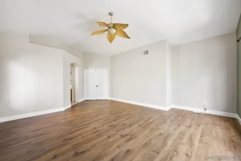 a view of empty room with wooden floor and ceiling fan