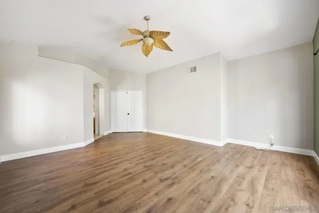 a view of empty room with wooden floor and ceiling fan