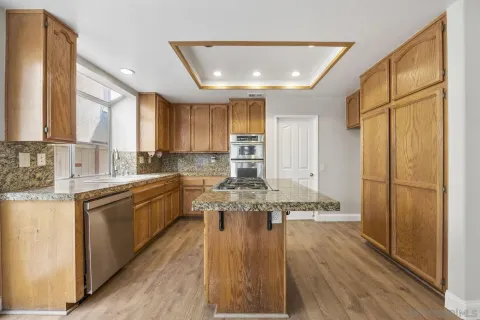 a kitchen with stainless steel appliances granite countertop wooden floors a stove and a refrigerator