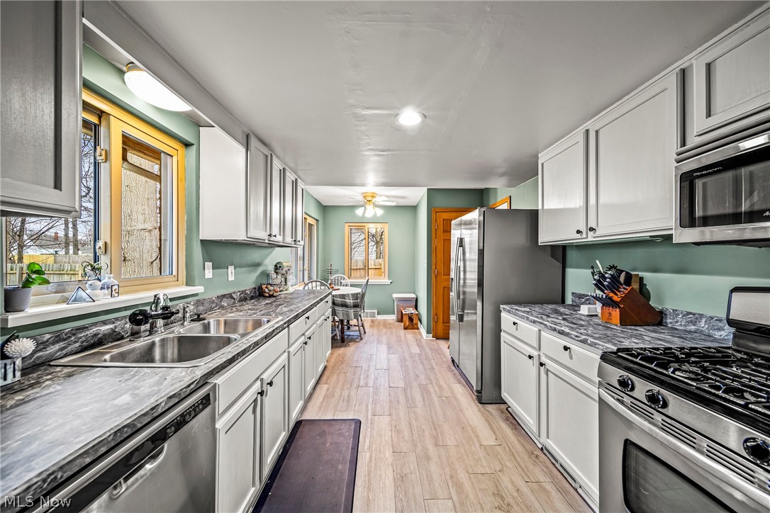 Kitchen with sink, stainless steel appliances, light wood-type flooring, and white cabinetry