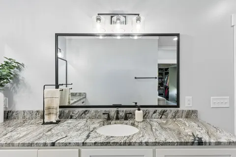 a bedroom with a bed a mirror on the dresser and a table