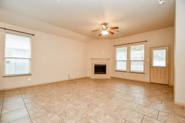 an empty room with windows and fireplace