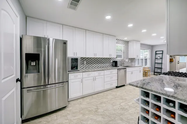 a large kitchen with stainless steel appliances granite countertop a stove sink and cabinets