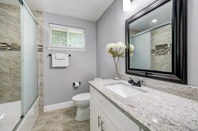 a bathroom with a granite countertop sink toilet and mirror
