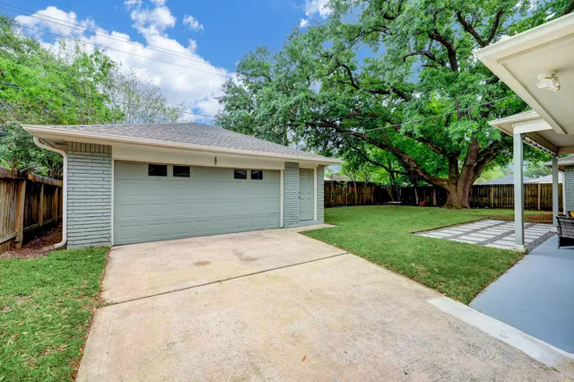 a backyard of a house with plants and large tree