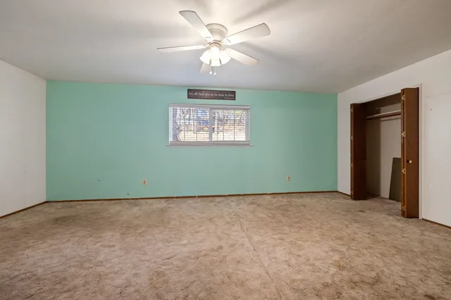 an empty room with a window and a ceiling fan