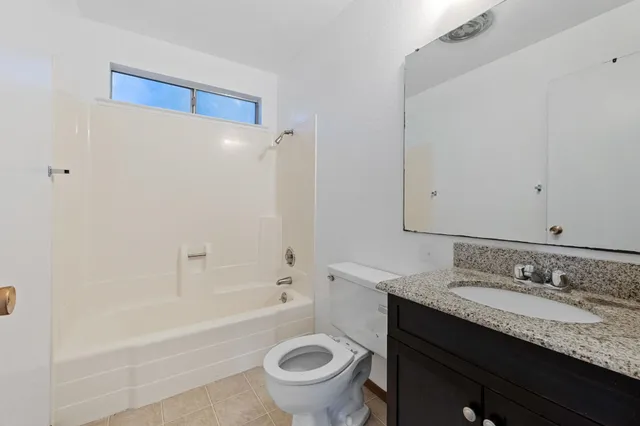 a bathroom with a granite countertop sink a toilet and bathtub