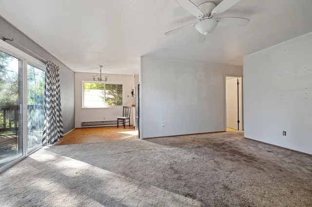 an empty room with windows and ceiling fan
