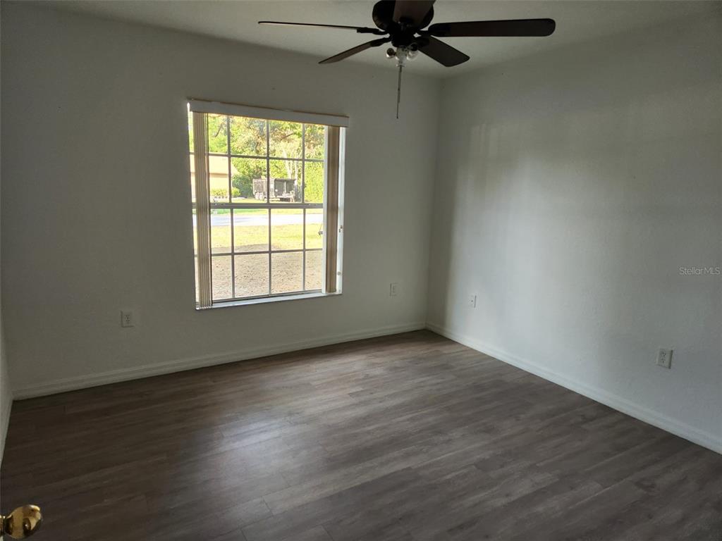 10154 Henderson Street Spring Hill, FL 34608 - Photo 14 of 19 an empty room with wooden floor fan and windows