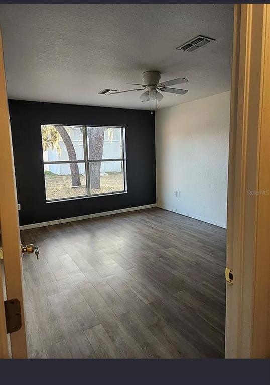 10154 Henderson Street Spring Hill, FL 34608 - Photo 6 of 19 an empty room with wooden floor and windows