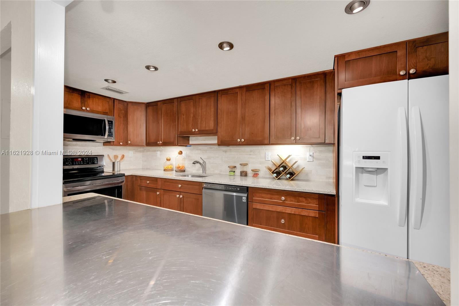 7927 Southwest 104th Street, Unit 108E Miami, FL 33156 - Photo 17 of 17 a kitchen with granite countertop a refrigerator and a stove top oven