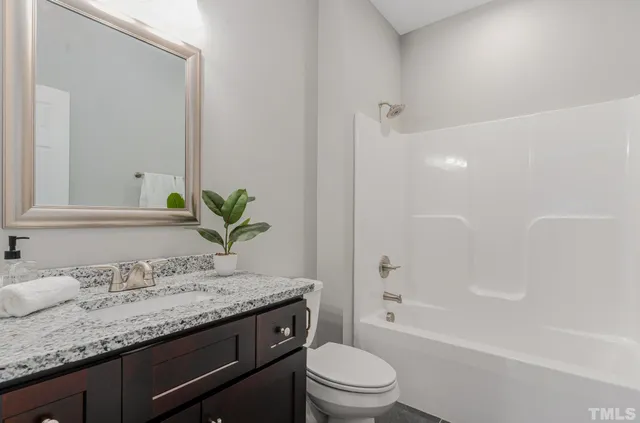 a bathroom with a granite countertop sink a toilet and shower