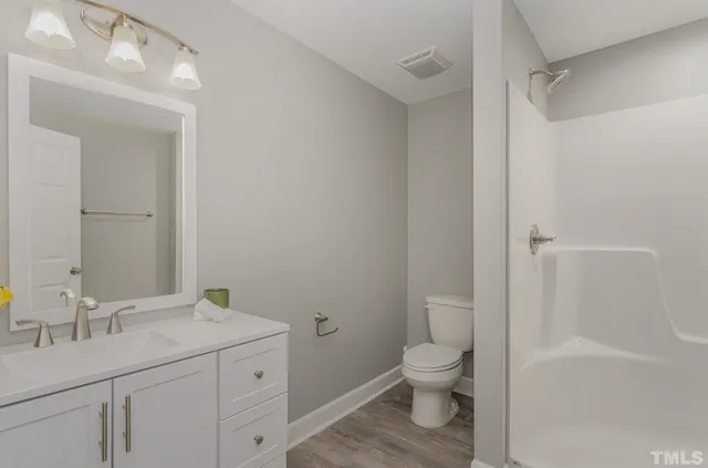 a bathroom with a granite countertop toilet a sink and a mirror