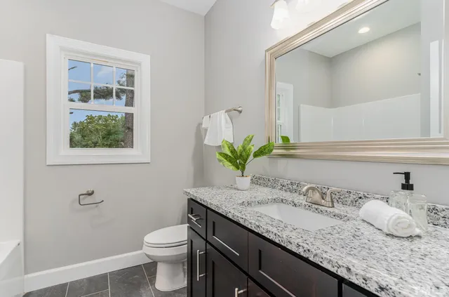 a bathroom with a granite countertop sink and a mirror