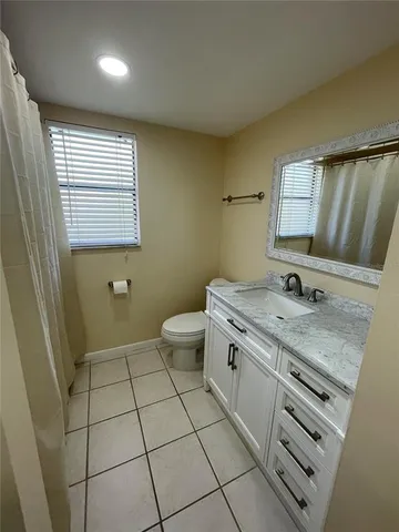a bathroom with a granite countertop sink a toilet and mirror