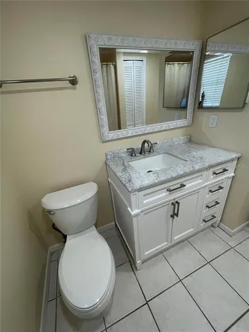 a bathroom with a granite countertop toilet sink and mirror