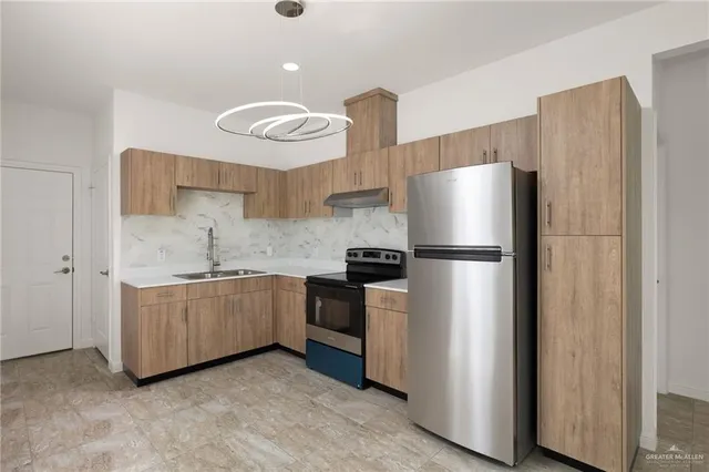 a kitchen with stainless steel appliances granite countertop a refrigerator and a stove top oven