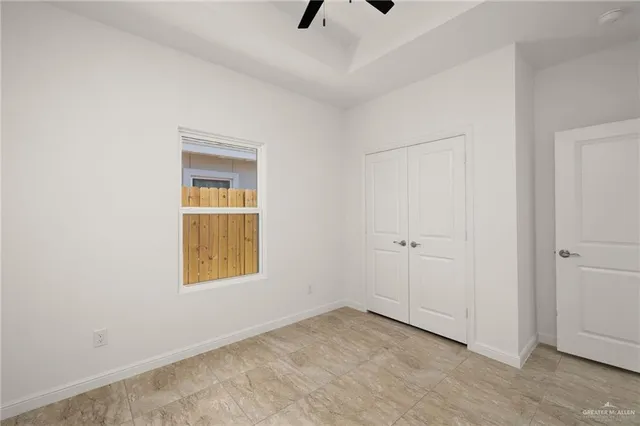 a view of an empty room with ceiling fan and window