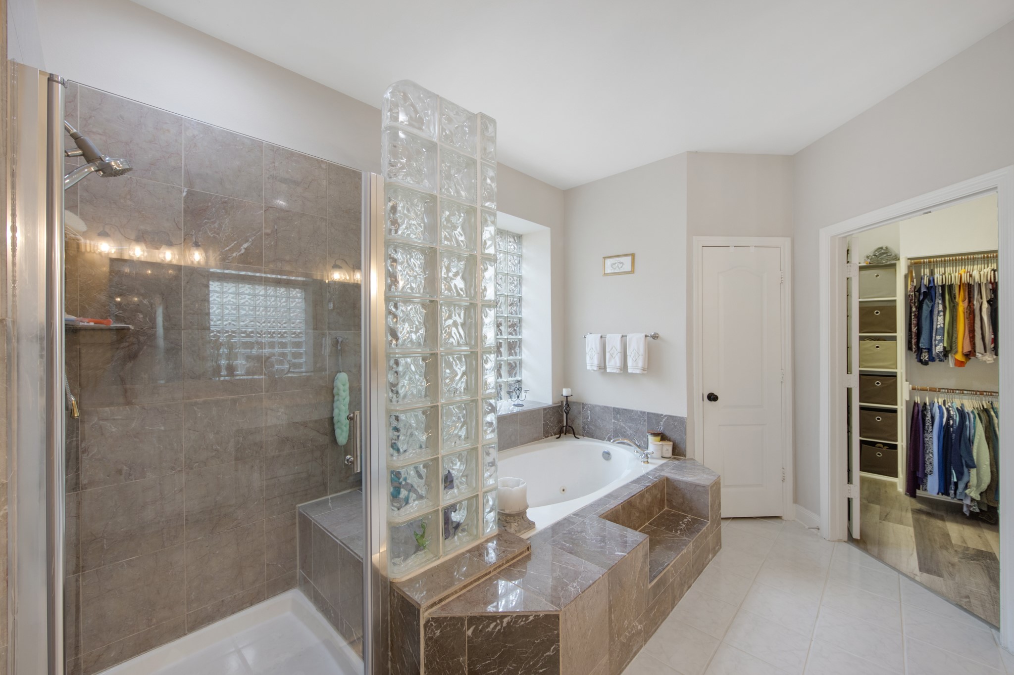 9510 Ashdown Forest Drive Spring, TX 77379 - Photo 24 of 50 PRIMARY BATHROOM – luxurious jetted soaking tub with elegant tile surround offers the perfect place to relax and unwind. Glass block windows provide privacy while allowing abundant natural light.
