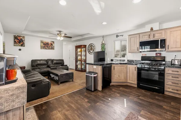 a kitchen with stainless steel appliances kitchen island granite countertop a stove top oven a sink dishwasher a dining table and chairs with wooden floor