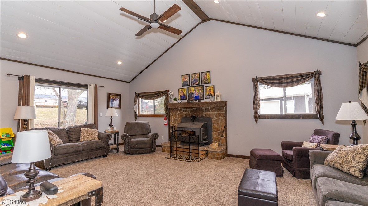 13962 Nickel Plate Road Logan, OH 43138 - Photo 11 of 46 Carpeted living room featuring ceiling fan, a wood stove, beam ceiling, high vaulted ceiling, and a fireplace
