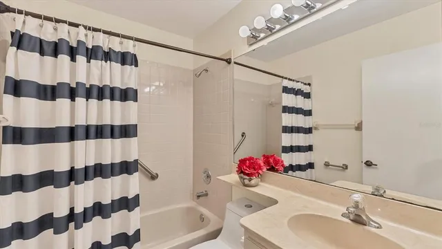 a bathroom with a sink a toilet a shower curtain and a mirror