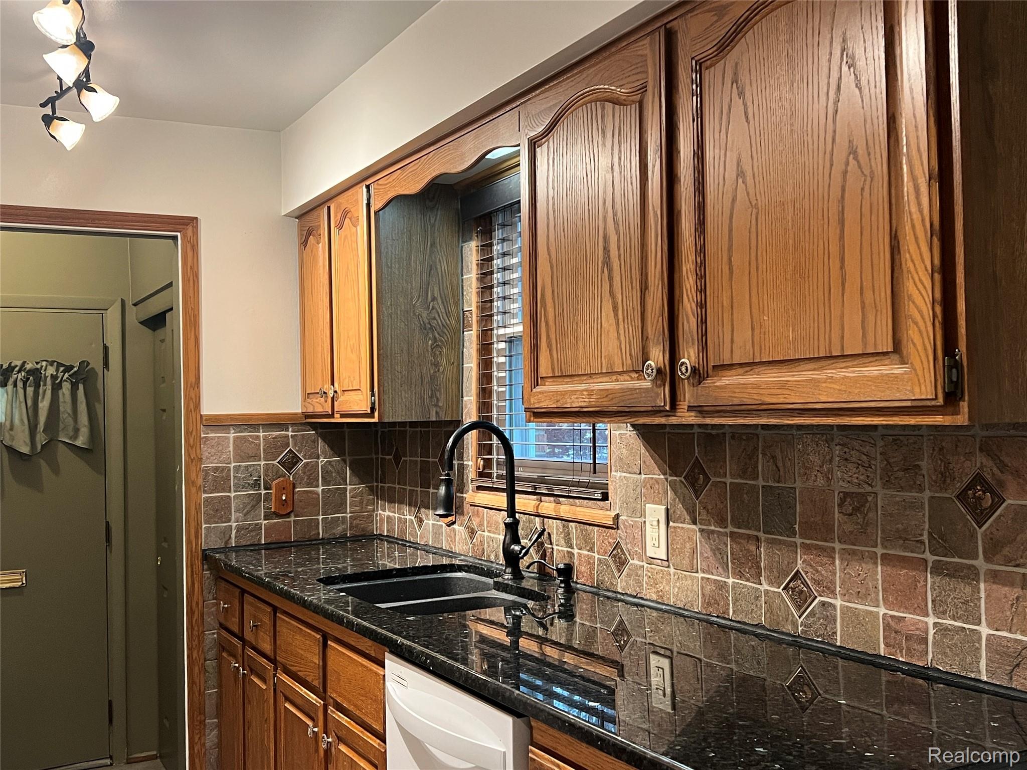 36795 Greenbush Road Wayne, MI 48184 - Photo 2 of 61 Kitchen with decorative backsplash, dark stone counters, brown cabinets, and white dishwasher