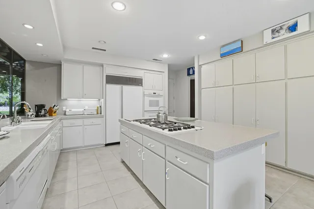 a kitchen that has a sink a stove top oven a refrigerator and white cabinets