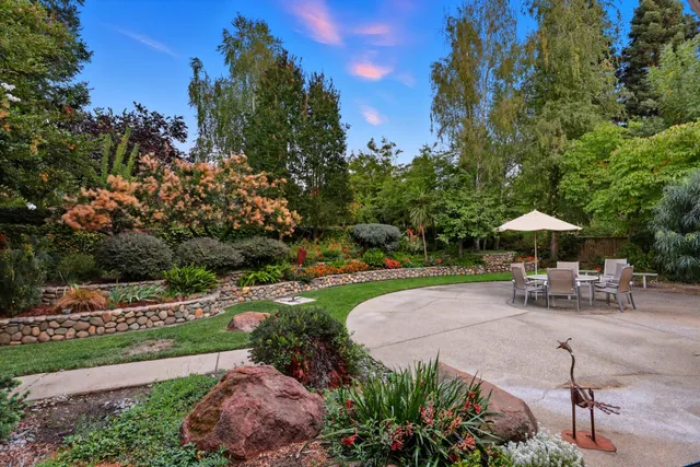 a view of a garden with a table and chairs under an umbrella