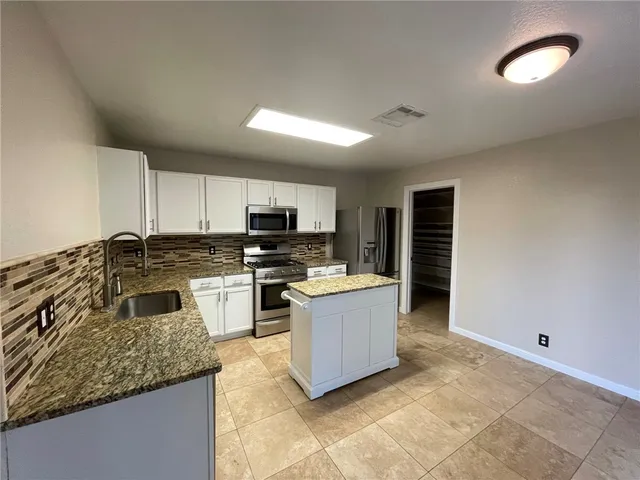 a kitchen with stainless steel appliances granite countertop a stove a sink and a microwave