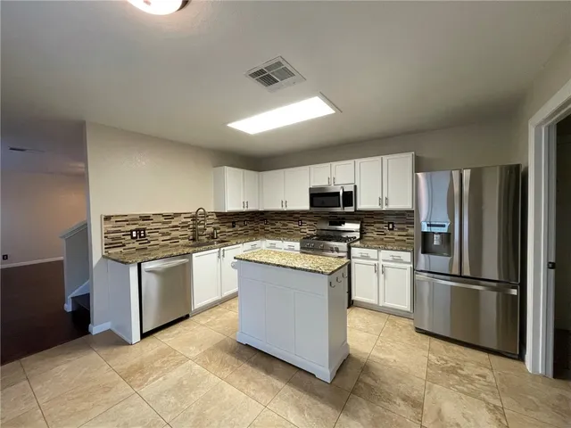 a view of a kitchen with a sink and dishwasher a stove top oven with wooden floor