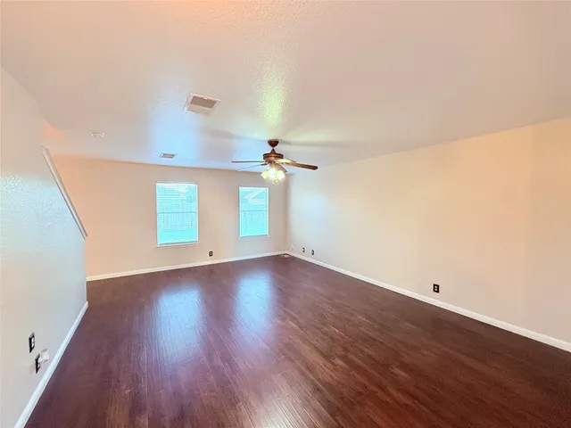 a view of a room with wooden floor and ceiling fan