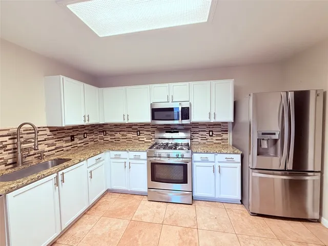 a kitchen with stainless steel appliances granite countertop a stove a sink and a refrigerator