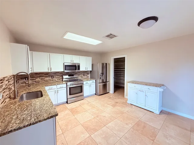a kitchen with granite countertop a stove cabinets and microwave
