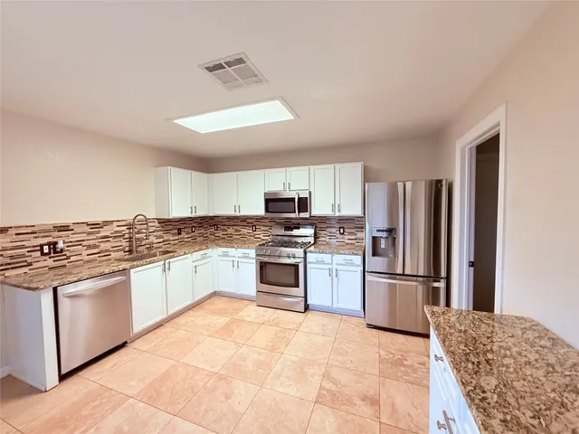 a kitchen with stainless steel appliances granite countertop a refrigerator stove and sink